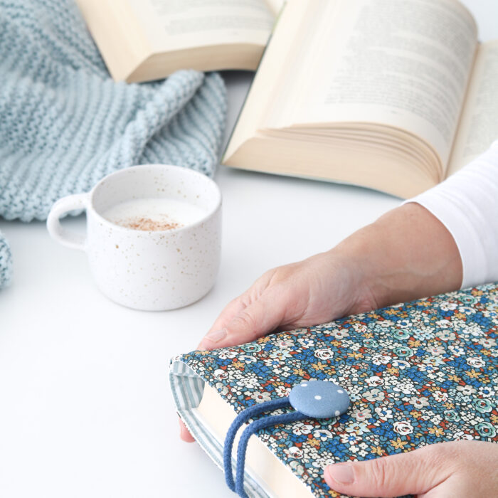 Funda de Libro LIBERTY BLUE con tela estampada en flores azules, blancas y marrones combinada con un forro interior de rayas en blanco y azul.