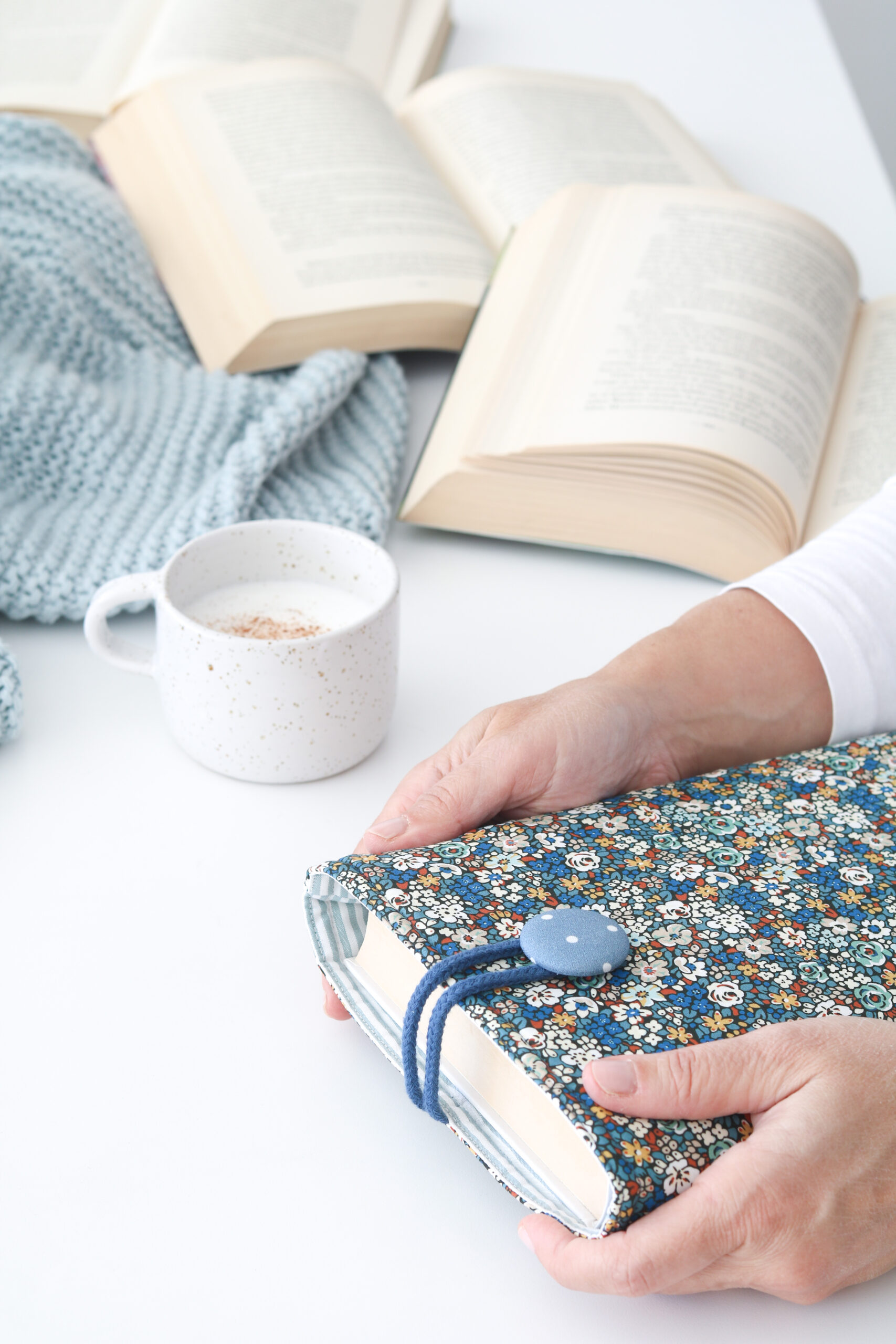 Funda de Libro LIBERTY BLUE con tela estampada en flores azules, blancas y marrones combinada con un forro interior de rayas en blanco y azul.