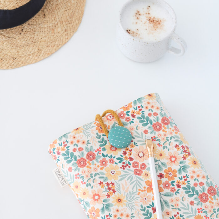 Funda de libro impermeable con estampado floral sobre fondo blanco roto, modelo Flower de Drapets.